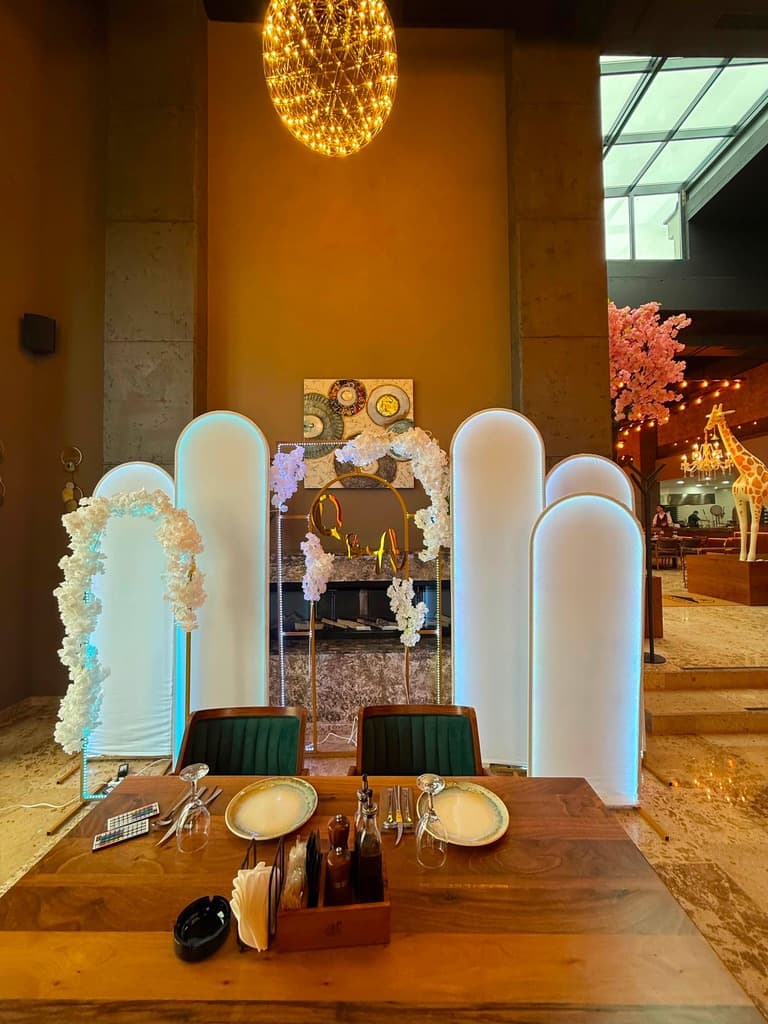 Sfond i punuar me harqe të bardha të ndriçuara dhe kompozime lulesh në restorant